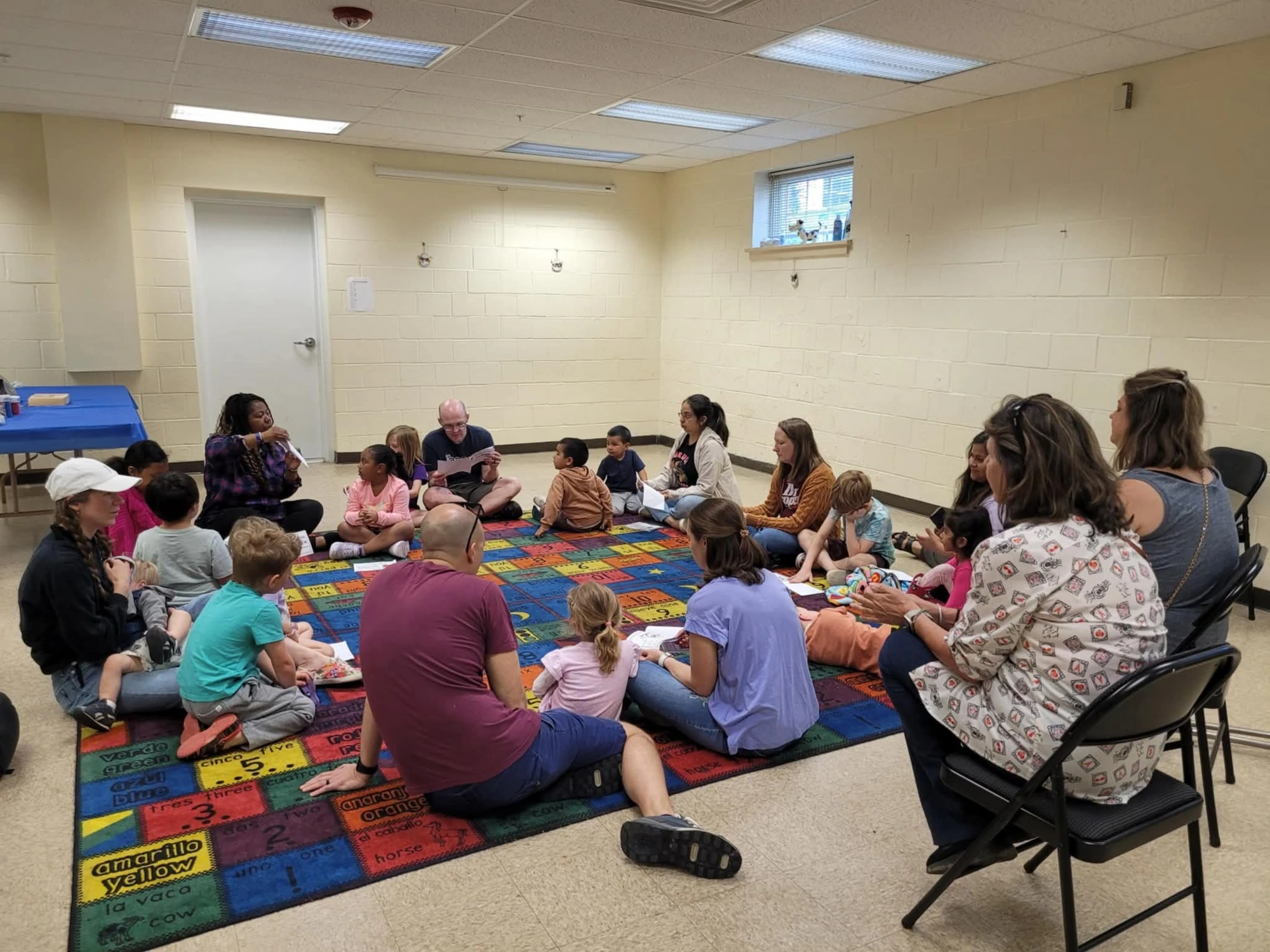 Children learning Spanish on a colorful alphabet rug at Alma y Lengua
