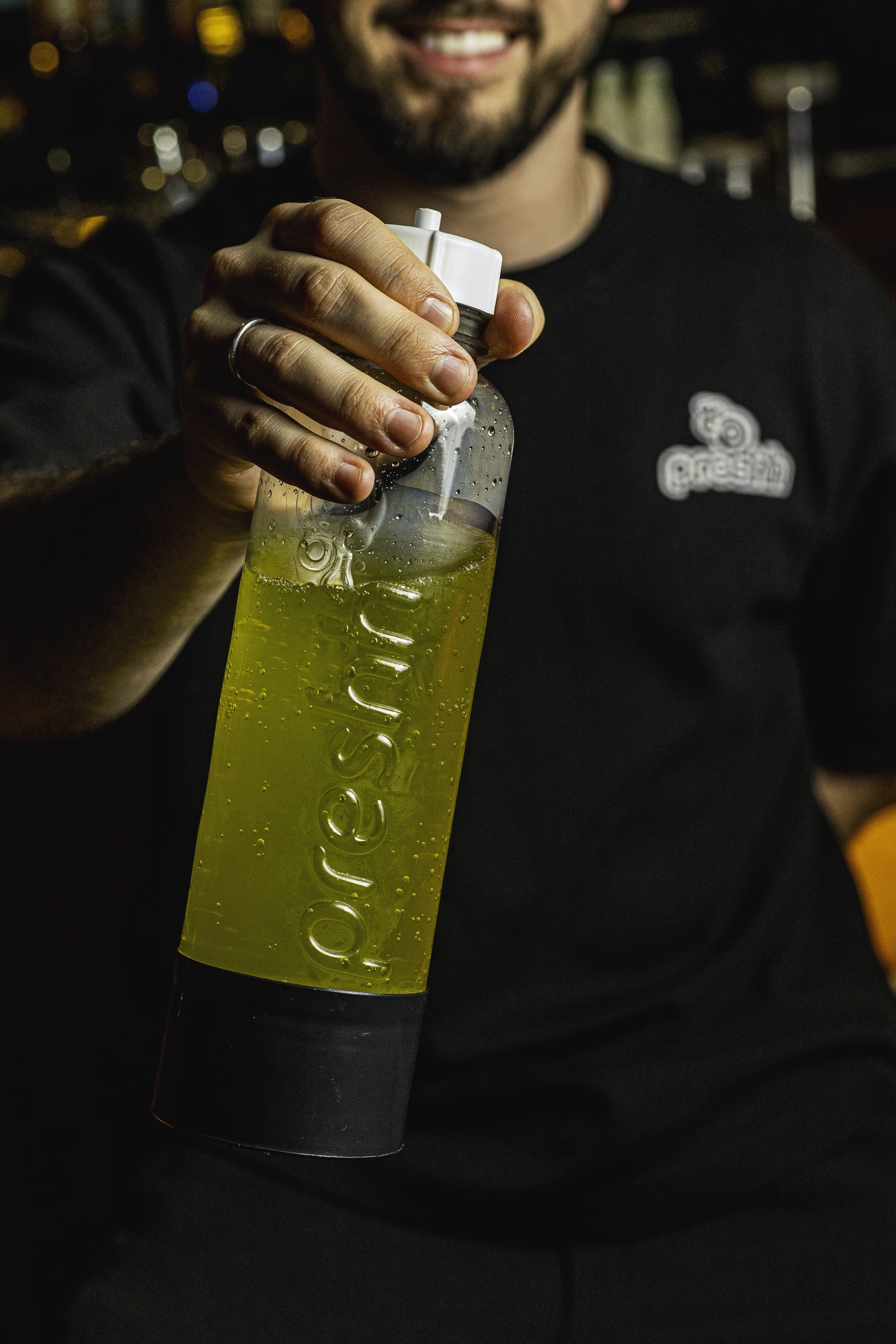 Close-up of a bartender's hands preparing a cocktail with Preshh carbonation gear