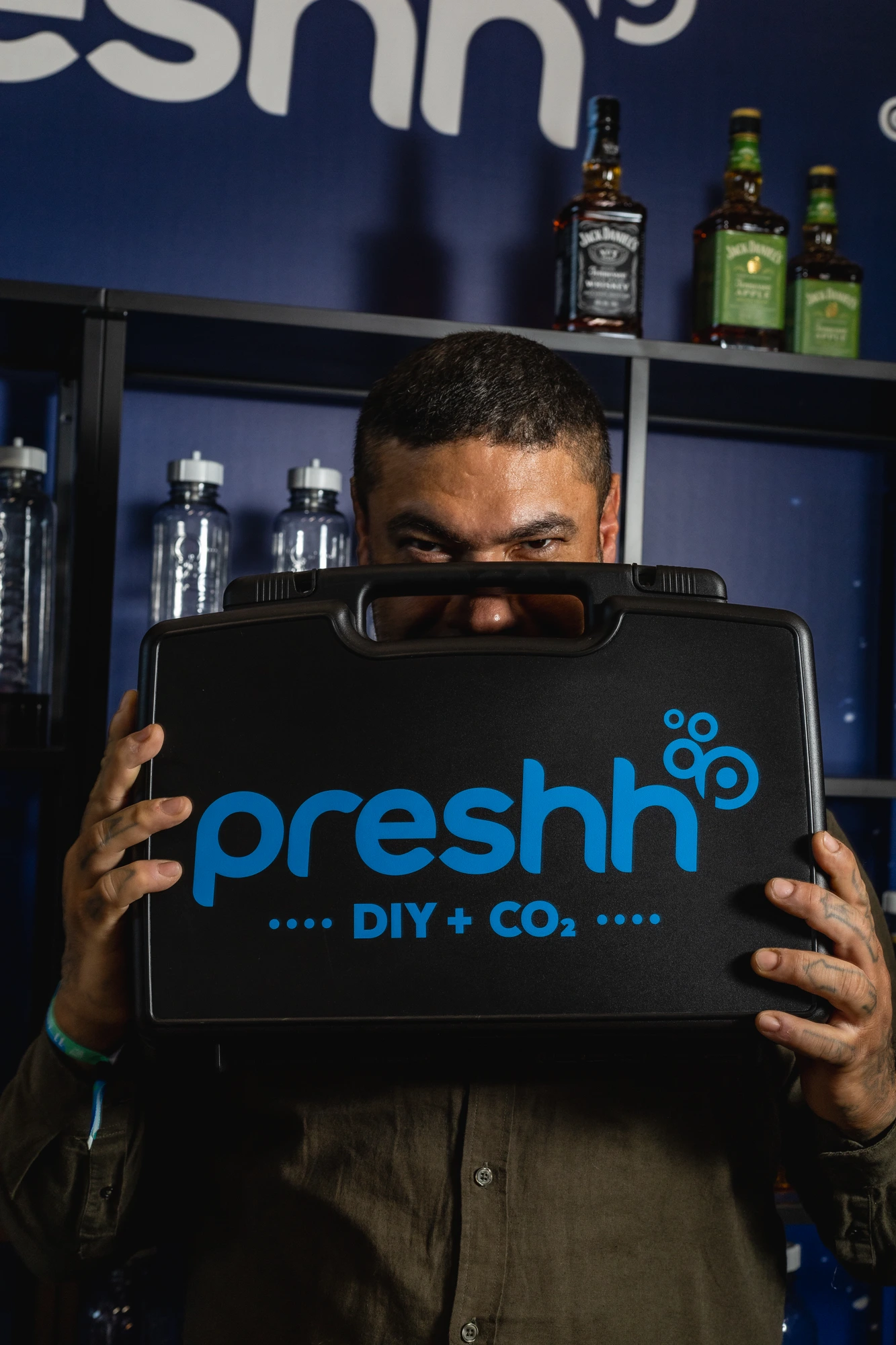 Bartender holding the Preshh portable carbonation case against a blue-lit backdrop
