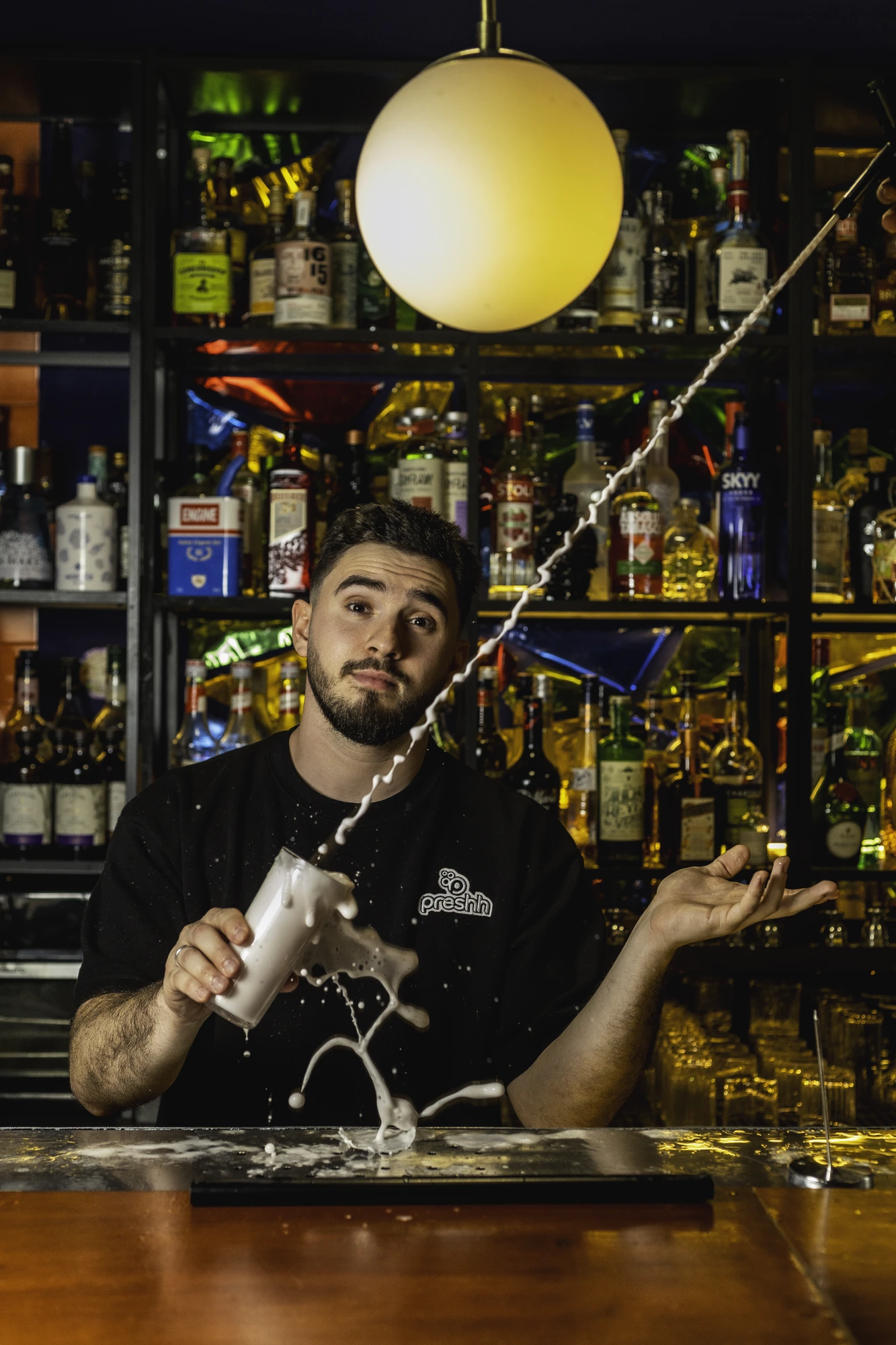 A bartender crafting a drink behind a bar with the Preshh system