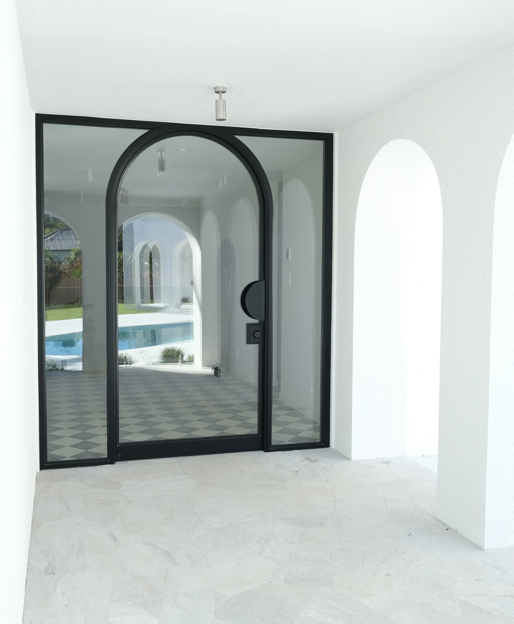 Bespoke arched steel door with a pool visible through the glass