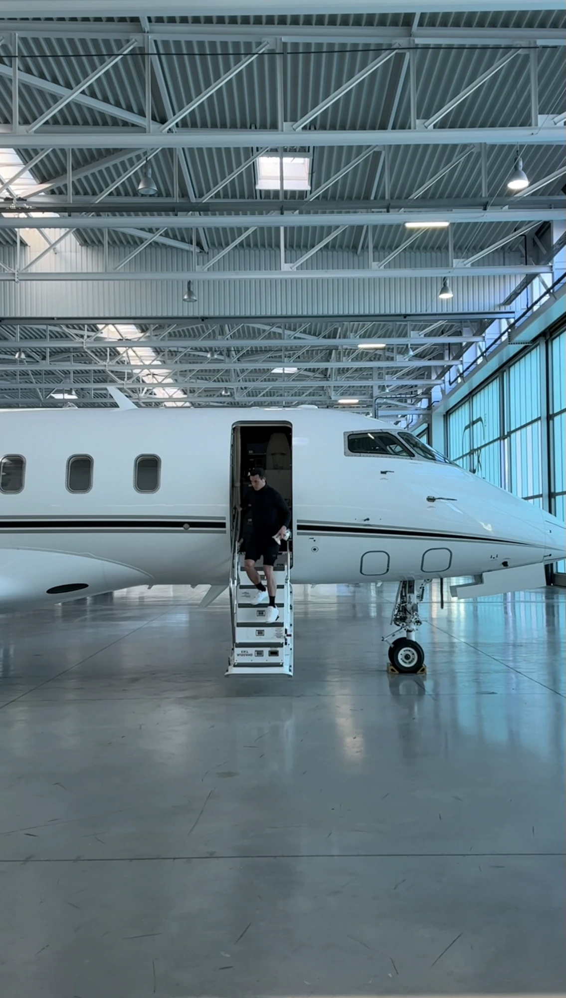 Nicolas Perot dos Santos stepping out of an ultra-long-range private jet inside a hangar — the operational reality of business aviation.