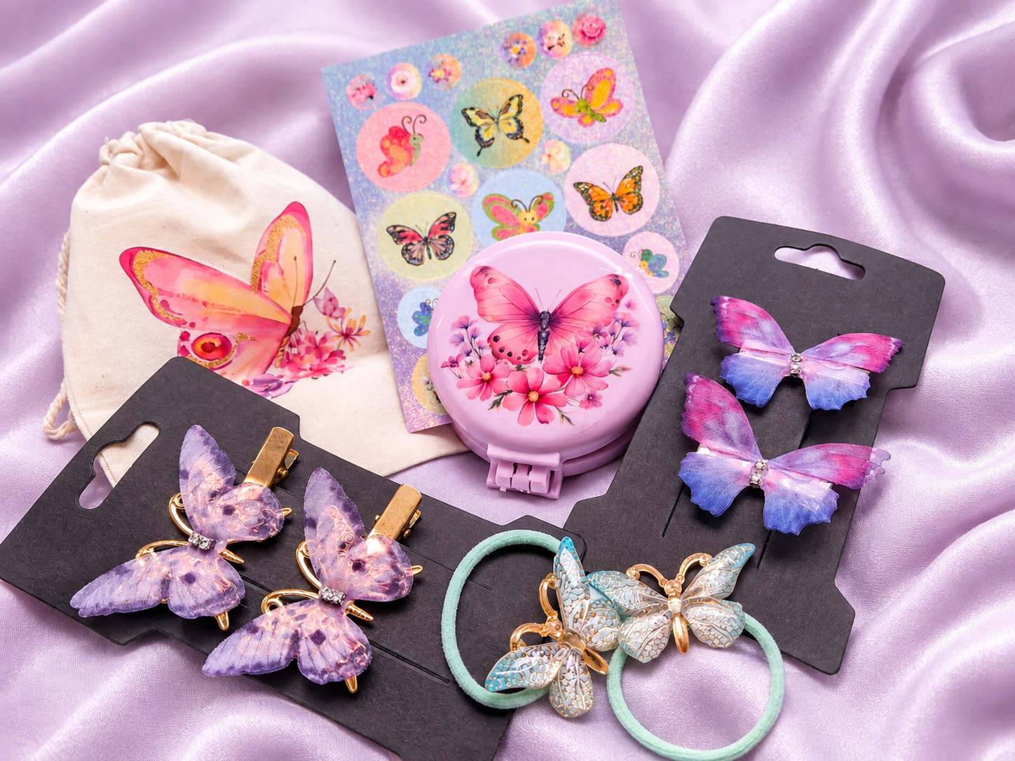 Me Amor Butterfly Collection on a lilac satin backdrop — cream drawstring gift bag with a printed pink butterfly, butterfly sticker sheet, pink pocket mirror with butterfly and floral design, satin pink and blue butterfly bow clips, lavender butterfly clips and butterfly-charm hair ties