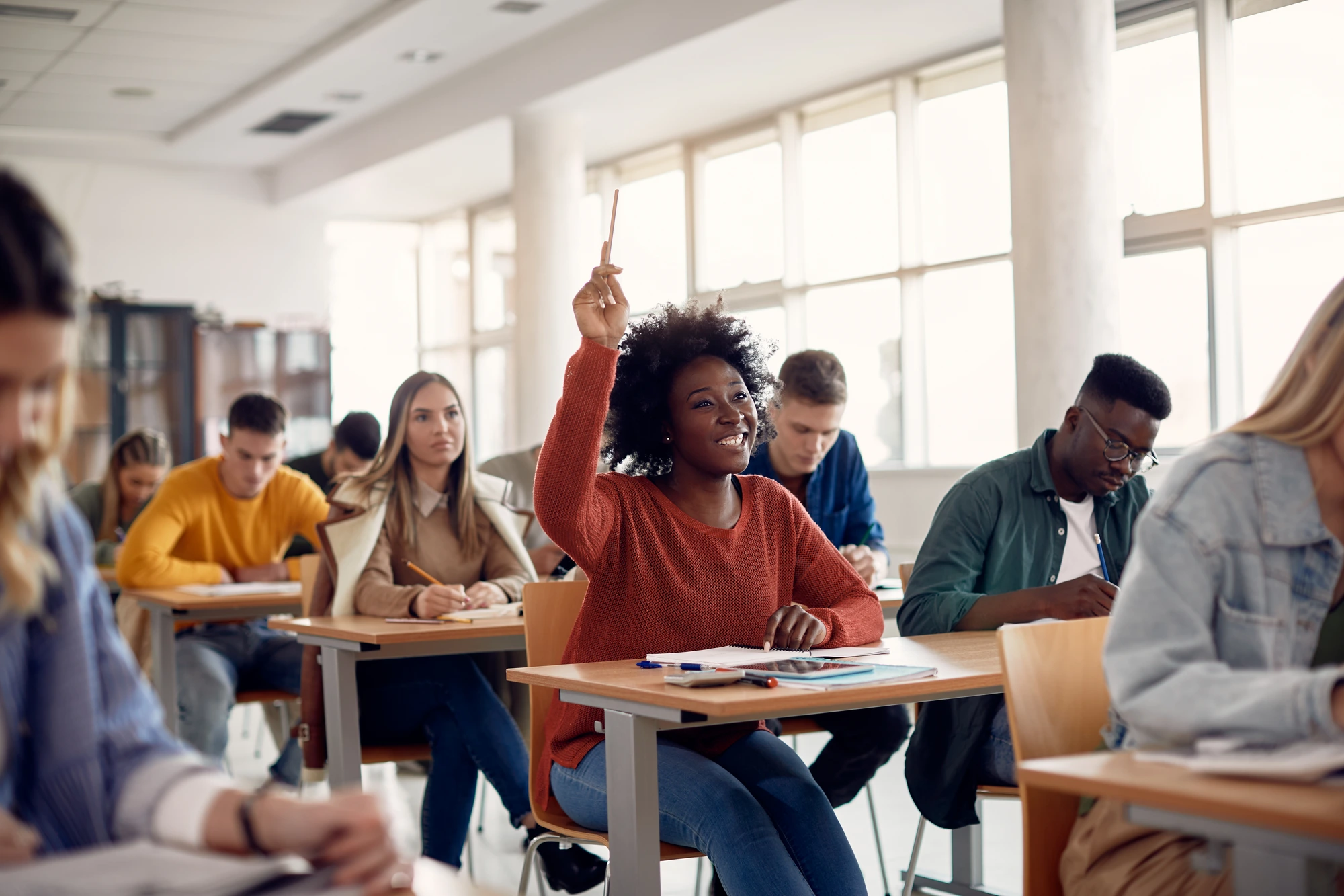 A student raising her hand in a diverse classroom — the many students one fund can reach