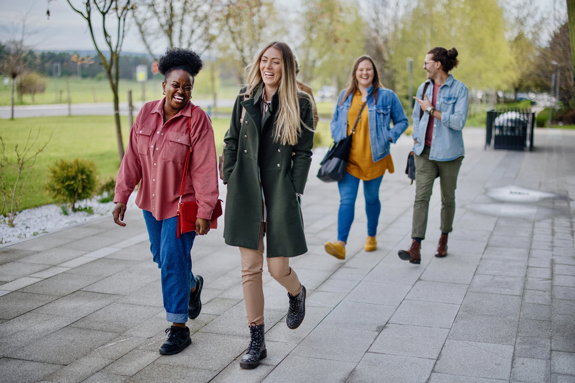 Four students walking together on a campus path, laughing