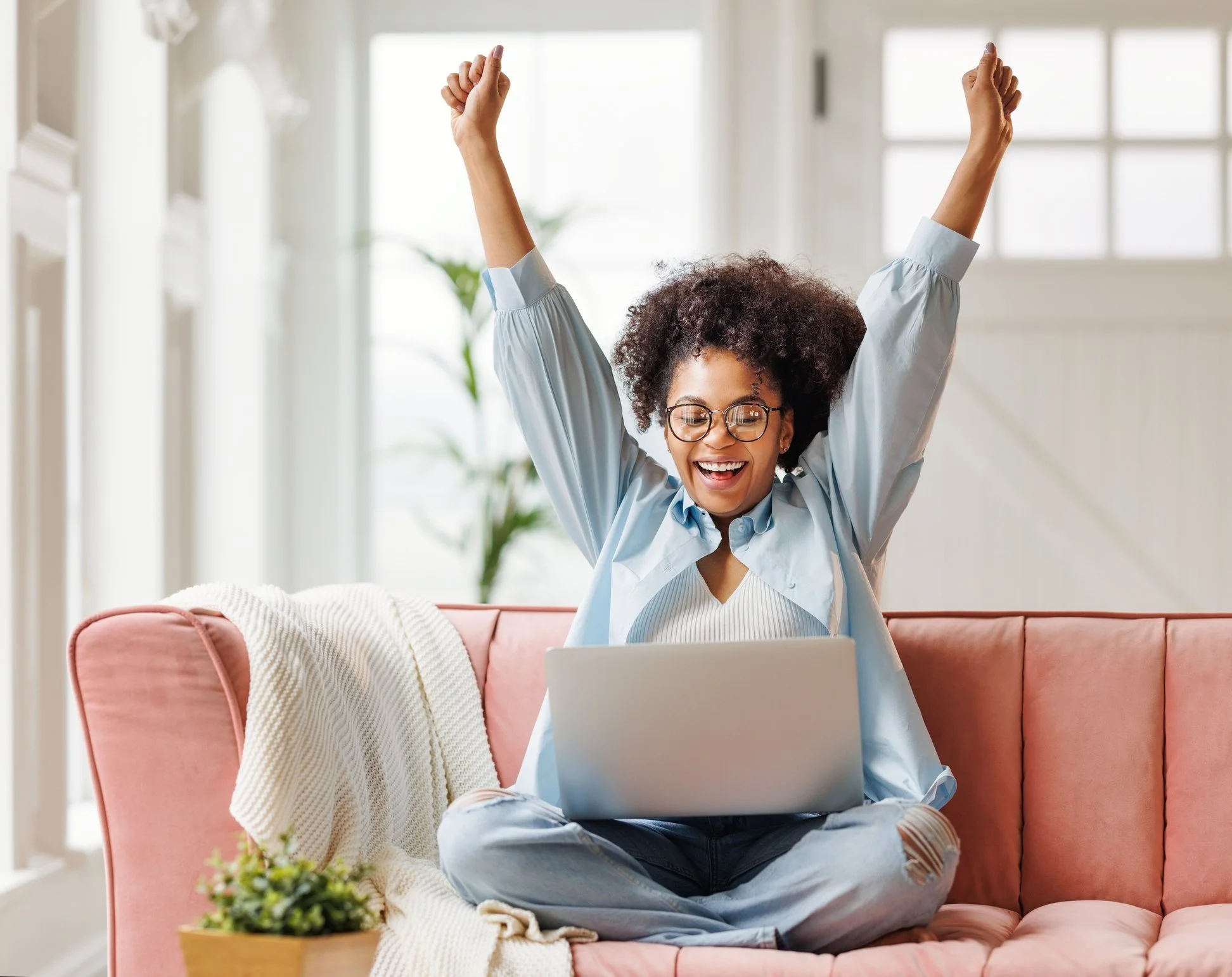 A student celebrating at her laptop, arms raised in the air — the moment a goal is met