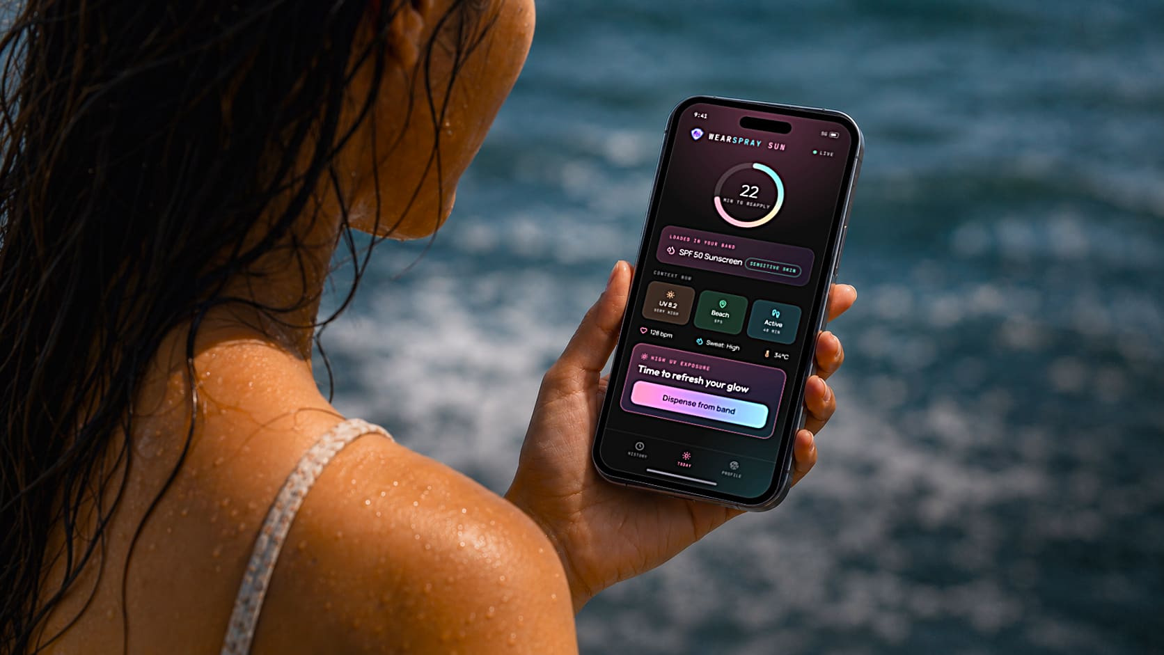 A woman at the ocean holding a phone showing the WearSpray Sun app with a 22-minute reapply timer and a Dispense from band prompt