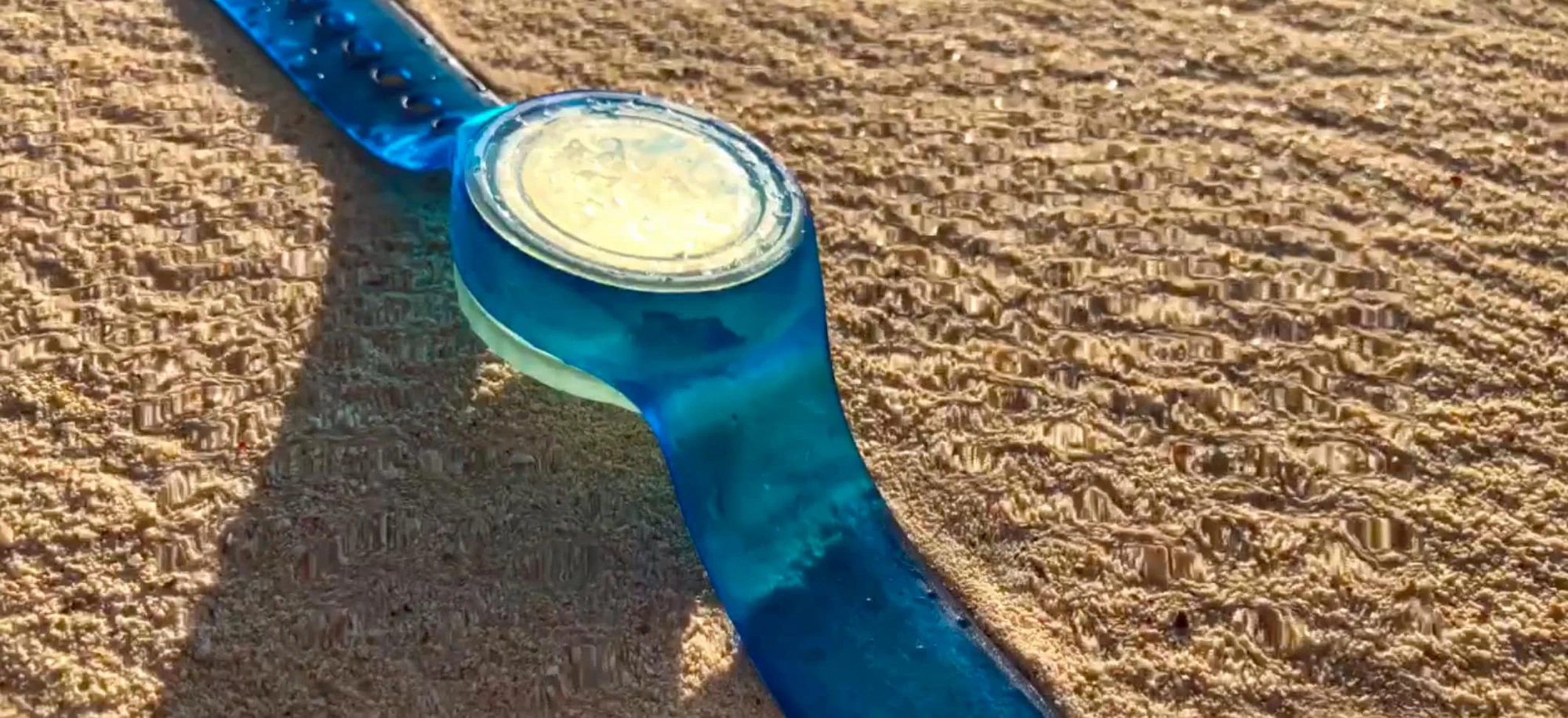 A blue WearSpray band on golden beach sand