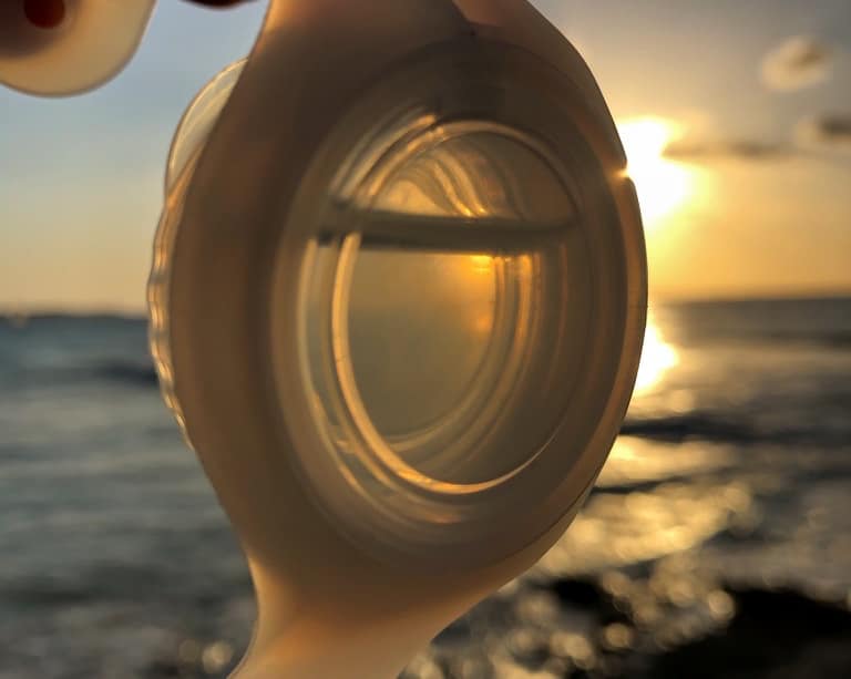 A translucent WearSpray band held to the sunset
