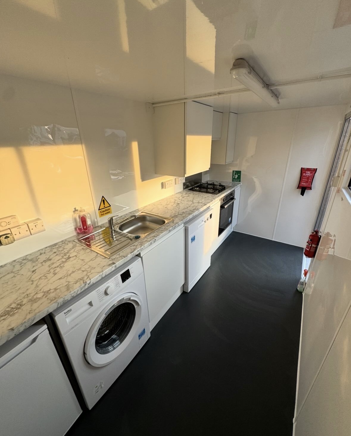 Interior of the mobile kitchen trailer showing sink, worktop, washing machine, gas hob and dishwasher