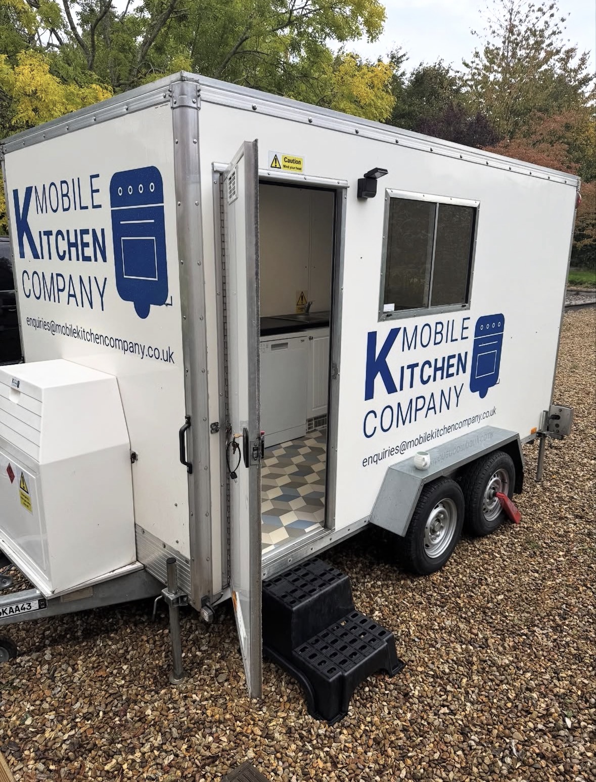 Temporary kitchen trailer exterior with door open, set up on site