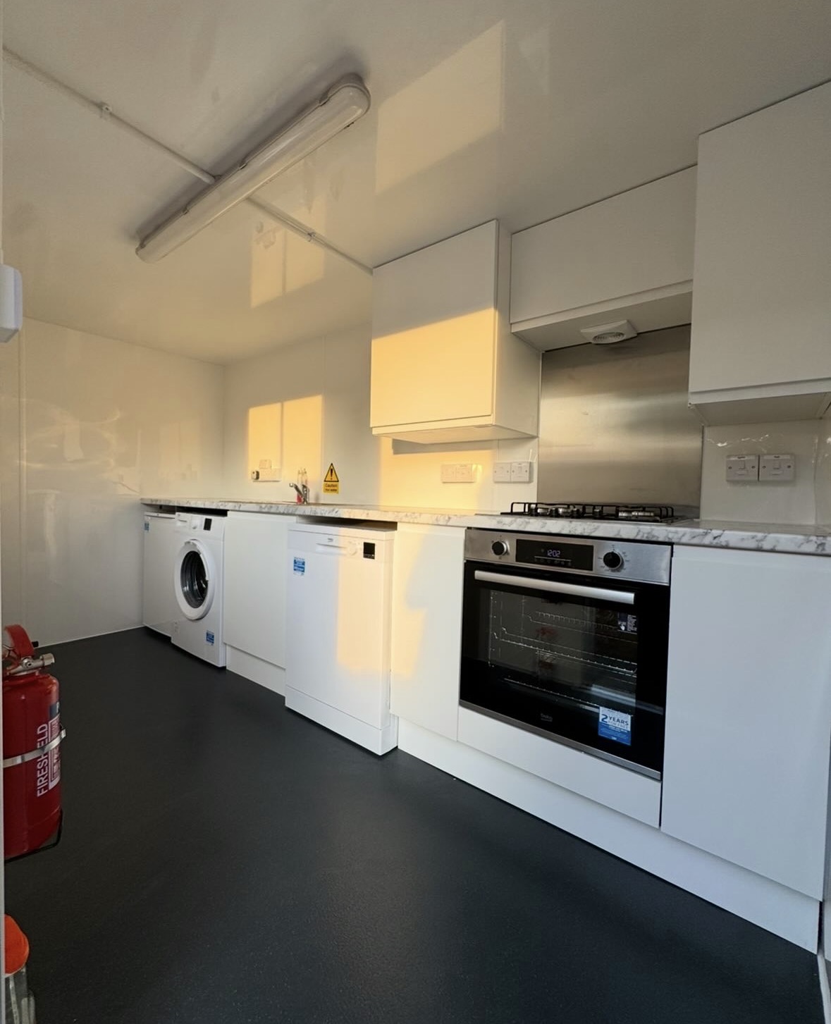 Interior of the temporary kitchen trailer showing oven, dishwasher and washing machine